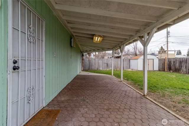 view of patio / terrace with a storage shed, a fenced backyard, and an outbuilding