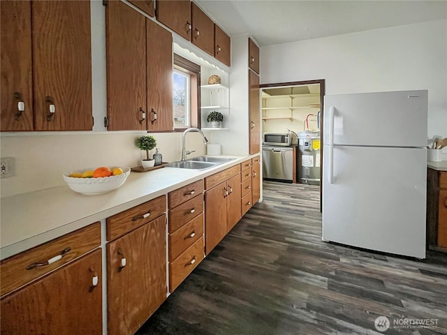 kitchen featuring dark wood-type flooring, a sink, light countertops, appliances with stainless steel finishes, and brown cabinetry