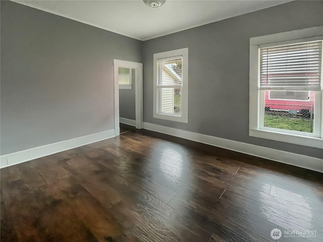 empty room with dark wood-type flooring and baseboards