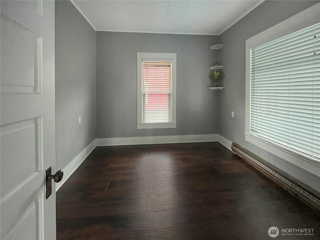 spare room with dark wood-type flooring, a baseboard radiator, and baseboards