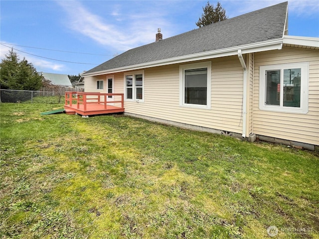 back of property featuring a yard, a chimney, fence, and a wooden deck