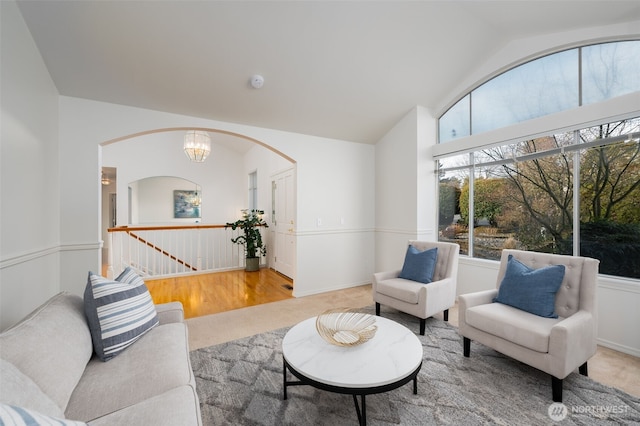 carpeted living room featuring vaulted ceiling and a notable chandelier