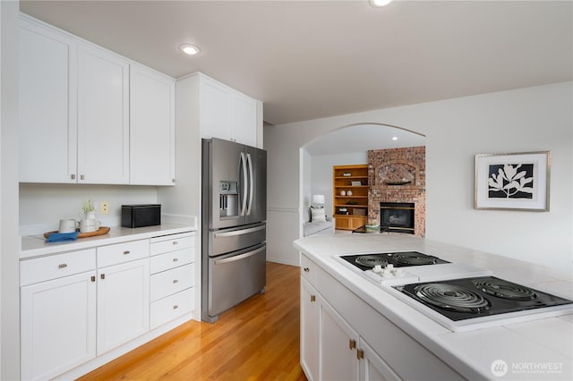 kitchen with stainless steel fridge, white cabinetry, light countertops, and stovetop with downdraft