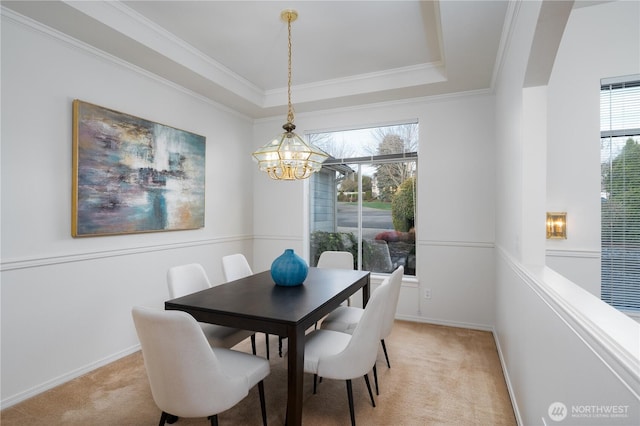 dining area with a tray ceiling, a notable chandelier, light colored carpet, ornamental molding, and baseboards