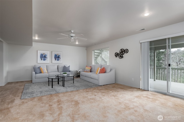 living room with carpet floors, visible vents, and ceiling fan