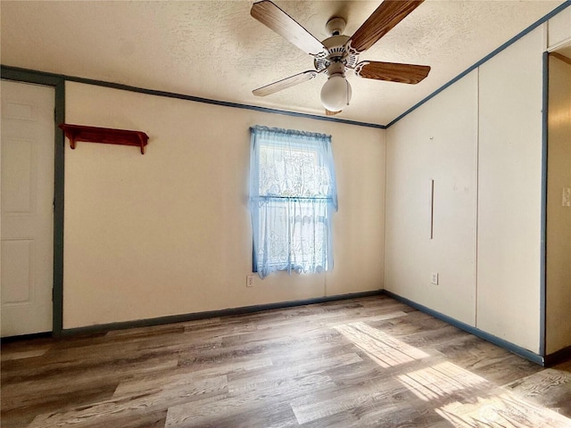 spare room with ceiling fan, a textured ceiling, baseboards, and wood finished floors