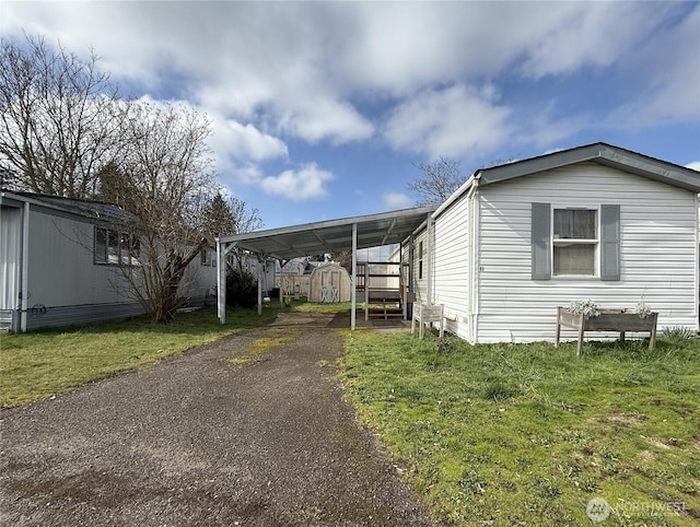 view of side of property with an attached carport, a lawn, a storage shed, an outdoor structure, and driveway