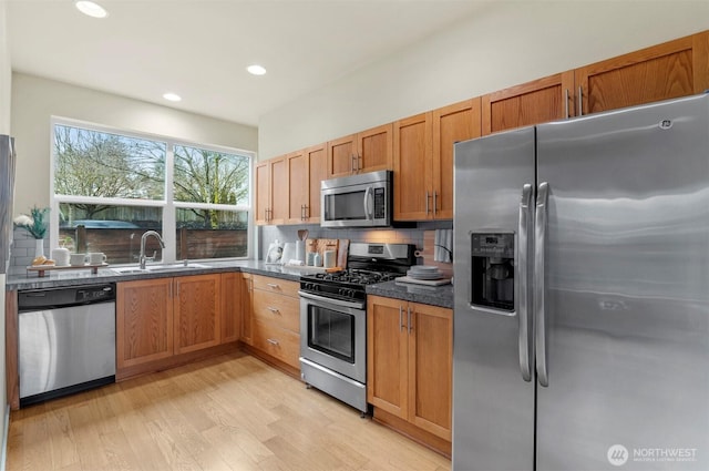 kitchen featuring stainless steel appliances, recessed lighting, backsplash, light wood-style floors, and a sink