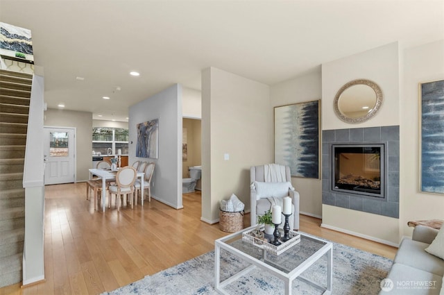 living area with a fireplace, recessed lighting, stairway, wood finished floors, and baseboards