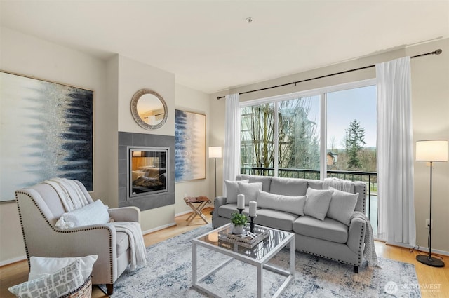 living area with a fireplace, baseboards, and wood finished floors