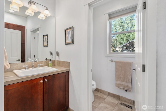 bathroom featuring toilet, vanity, visible vents, and baseboards