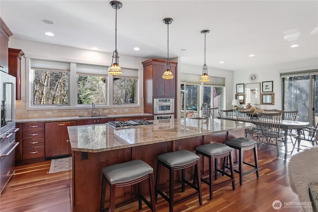 kitchen with tasteful backsplash, a kitchen island, dark wood-type flooring, stainless steel appliances, and a sink