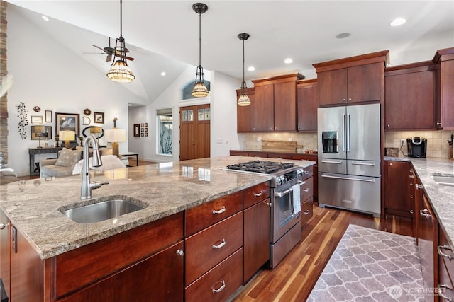 kitchen featuring a center island with sink, high end appliances, dark wood-style floors, open floor plan, and a sink