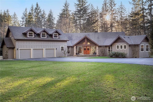 view of front of home featuring aphalt driveway, board and batten siding, an attached garage, and a front lawn