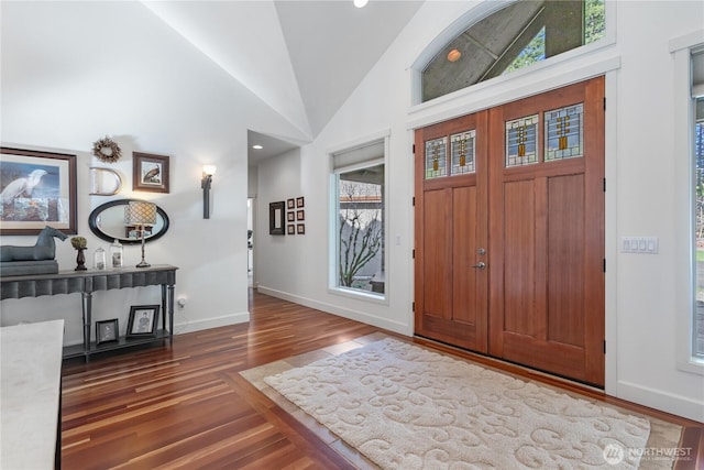 foyer entrance with high vaulted ceiling, wood finished floors, and baseboards