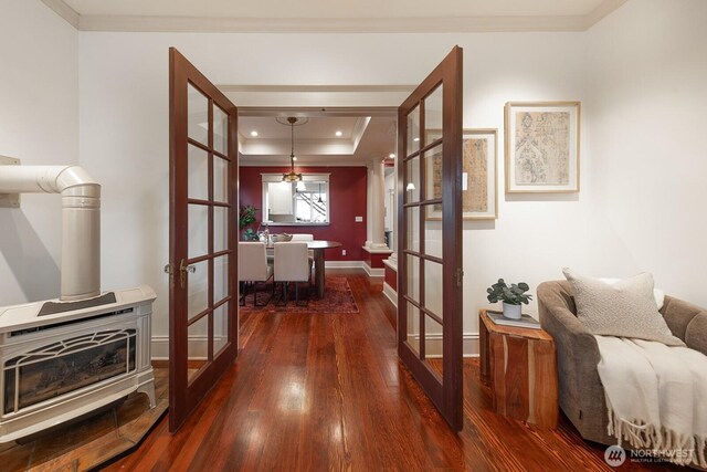 hallway featuring dark wood-type flooring, a tray ceiling, french doors, and ornamental molding