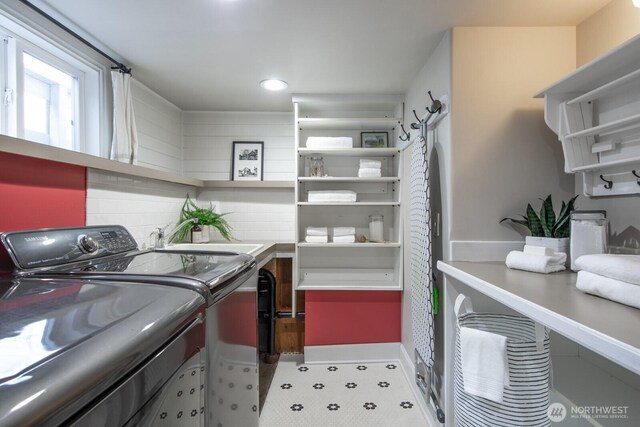 washroom featuring laundry area, washing machine and dryer, and a sink