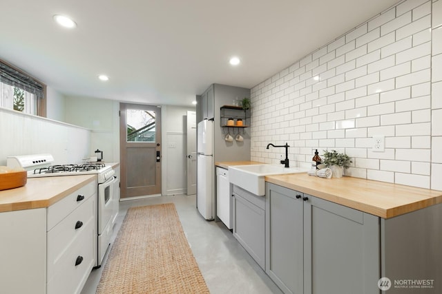 kitchen featuring open shelves, white appliances, wooden counters, and a sink