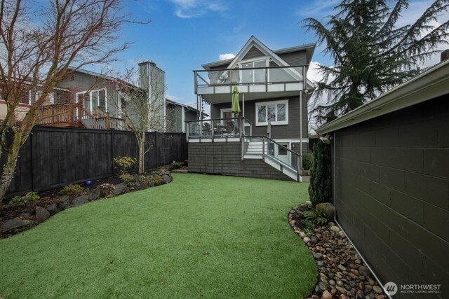 back of house with a fenced backyard, a yard, and a balcony