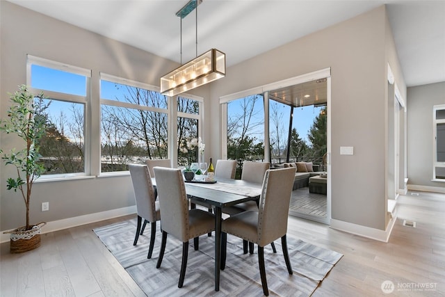 dining room with a notable chandelier, plenty of natural light, and light wood-style floors