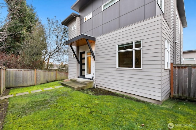 rear view of house featuring a fenced backyard and a yard