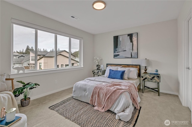 bedroom featuring visible vents, light carpet, and baseboards