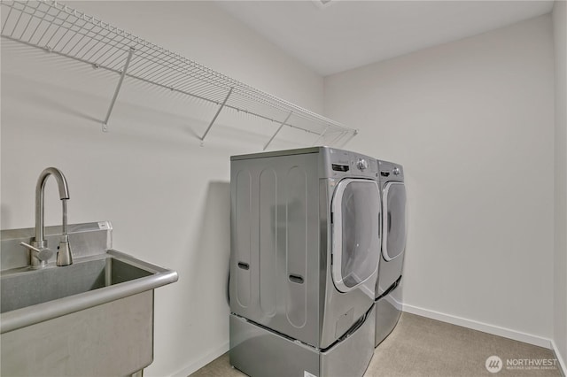 laundry room with laundry area, independent washer and dryer, a sink, and baseboards