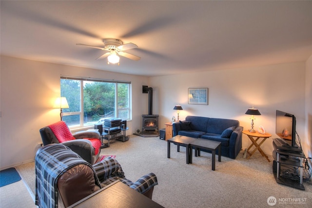 living room featuring carpet floors, a wood stove, and ceiling fan