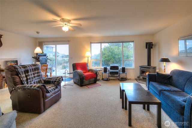 carpeted living room with a wood stove and ceiling fan