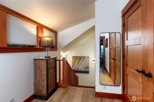 hall featuring baseboards, wood finished floors, and an upstairs landing