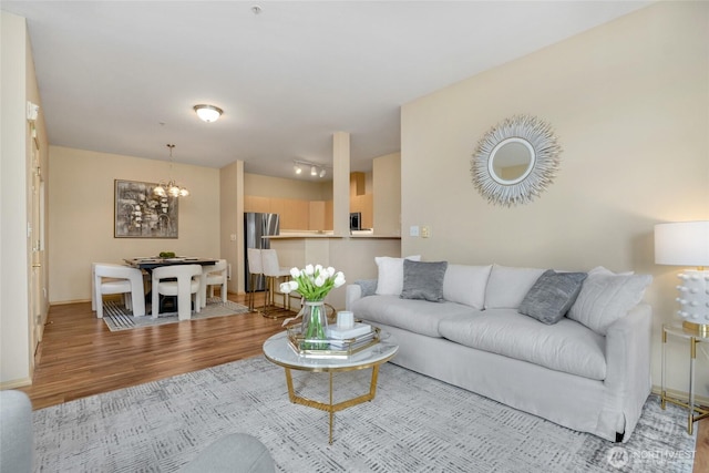 living room with light wood finished floors, baseboards, and an inviting chandelier