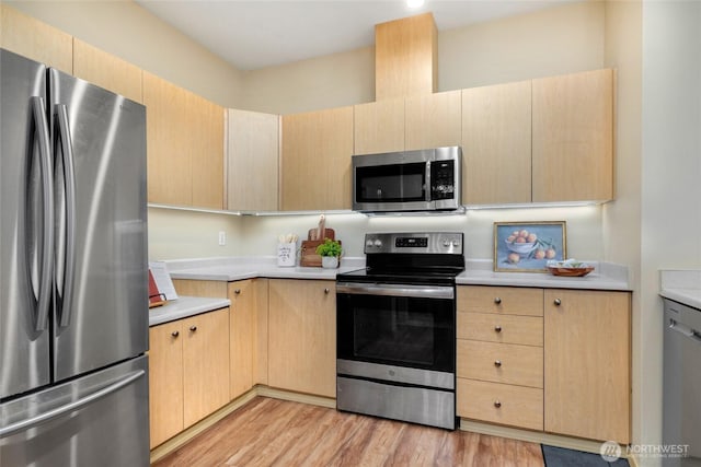 kitchen with light wood-type flooring, light brown cabinets, stainless steel appliances, and light countertops