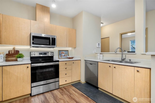 kitchen with light brown cabinetry, appliances with stainless steel finishes, light countertops, and a sink