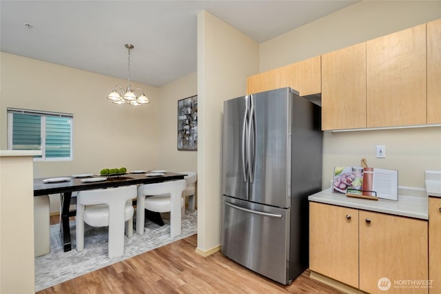 kitchen featuring a chandelier, light countertops, freestanding refrigerator, and light wood-style floors