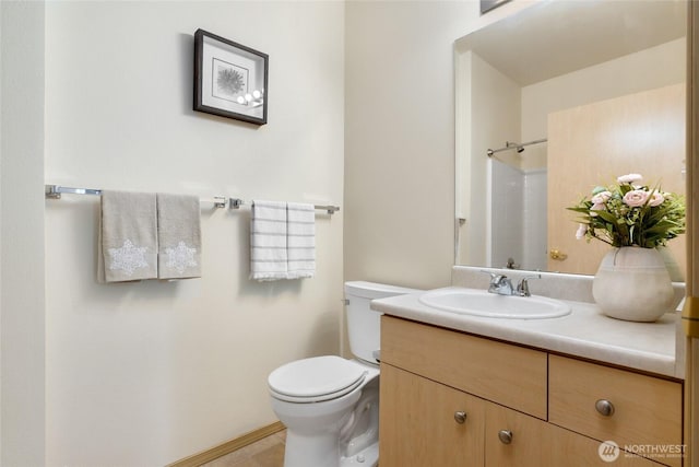 bathroom featuring toilet, walk in shower, and vanity