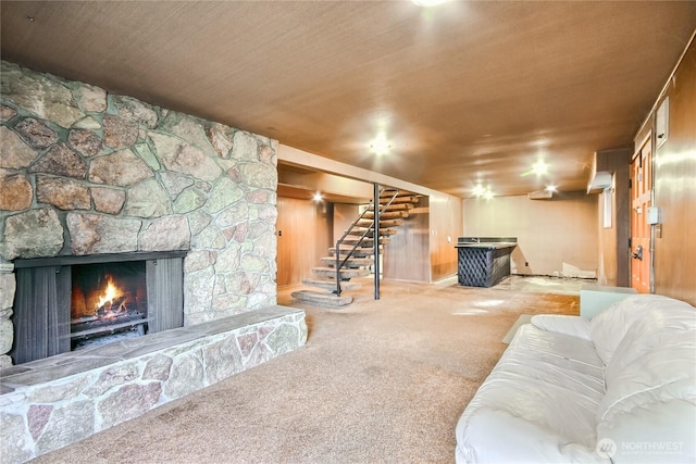 living room with stairway, carpet flooring, and a stone fireplace