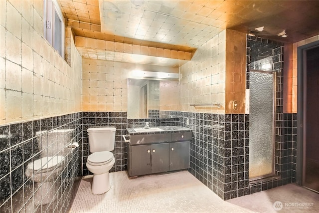 full bathroom with toilet, vanity, tile patterned flooring, and tile walls