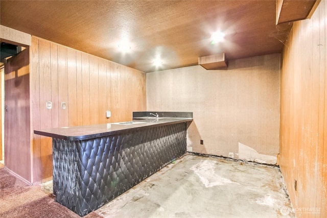 bar with concrete floors, wood walls, and a dry bar