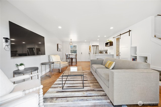 living area featuring baseboards, a barn door, light wood-type flooring, and recessed lighting