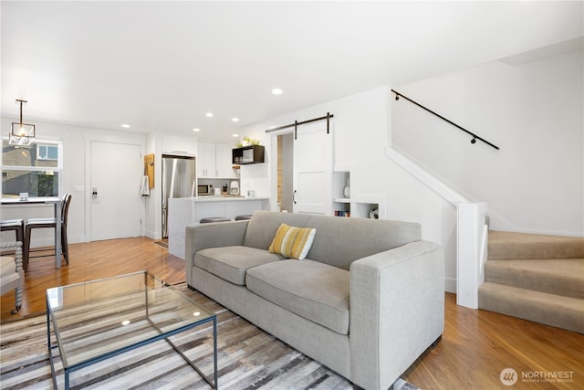 living area with stairs, recessed lighting, light wood-style flooring, and a barn door