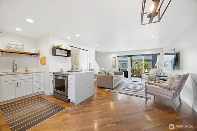 kitchen featuring a barn door, a sink, white cabinets, light countertops, and stainless steel electric range