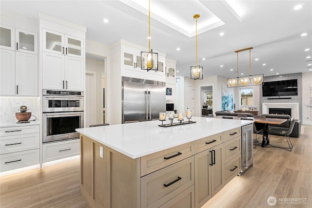 kitchen with stainless steel appliances, a spacious island, light countertops, and glass insert cabinets