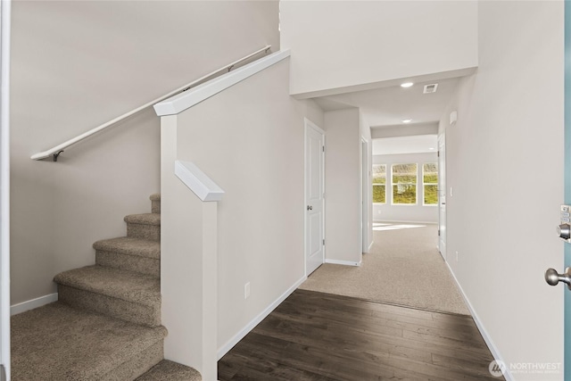 stairway featuring visible vents, baseboards, and wood finished floors