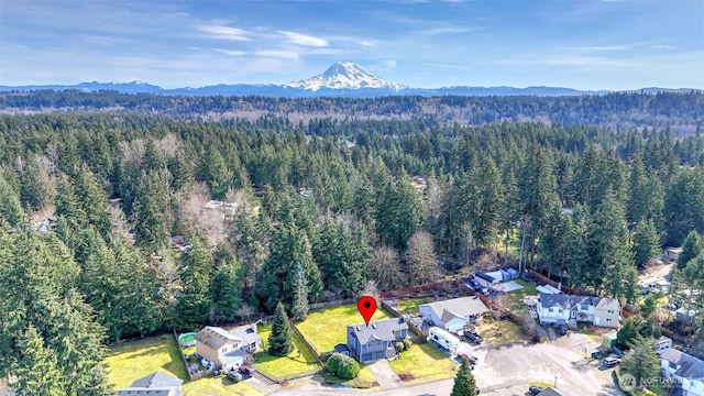 aerial view featuring a wooded view and a mountain view