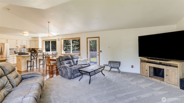 living room featuring vaulted ceiling, a notable chandelier, and light colored carpet