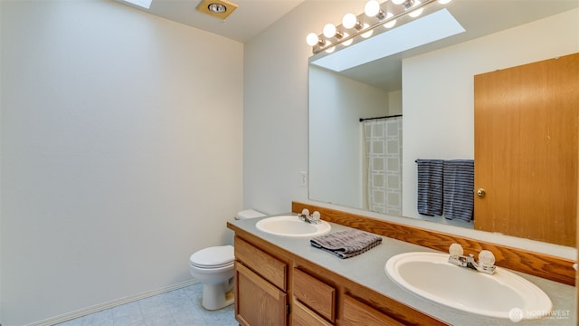 bathroom featuring toilet, a skylight, and a sink