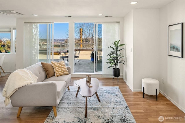 living area with visible vents, baseboards, wood finished floors, and recessed lighting