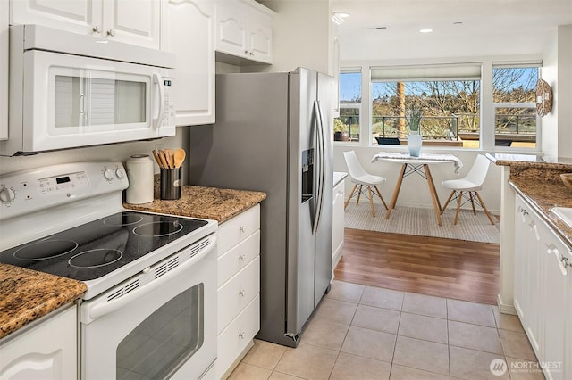 kitchen featuring light tile patterned floors, recessed lighting, white appliances, white cabinets, and dark stone counters