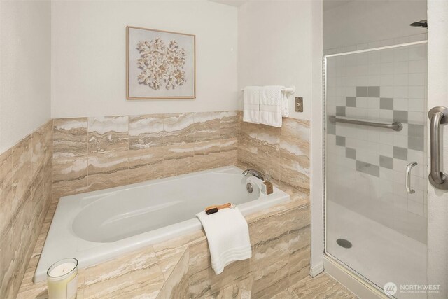 bathroom featuring a shower stall and a bath