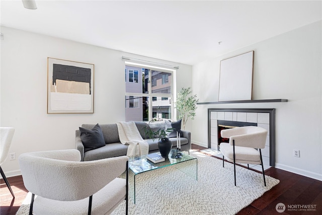 living room with a fireplace, baseboards, and wood finished floors